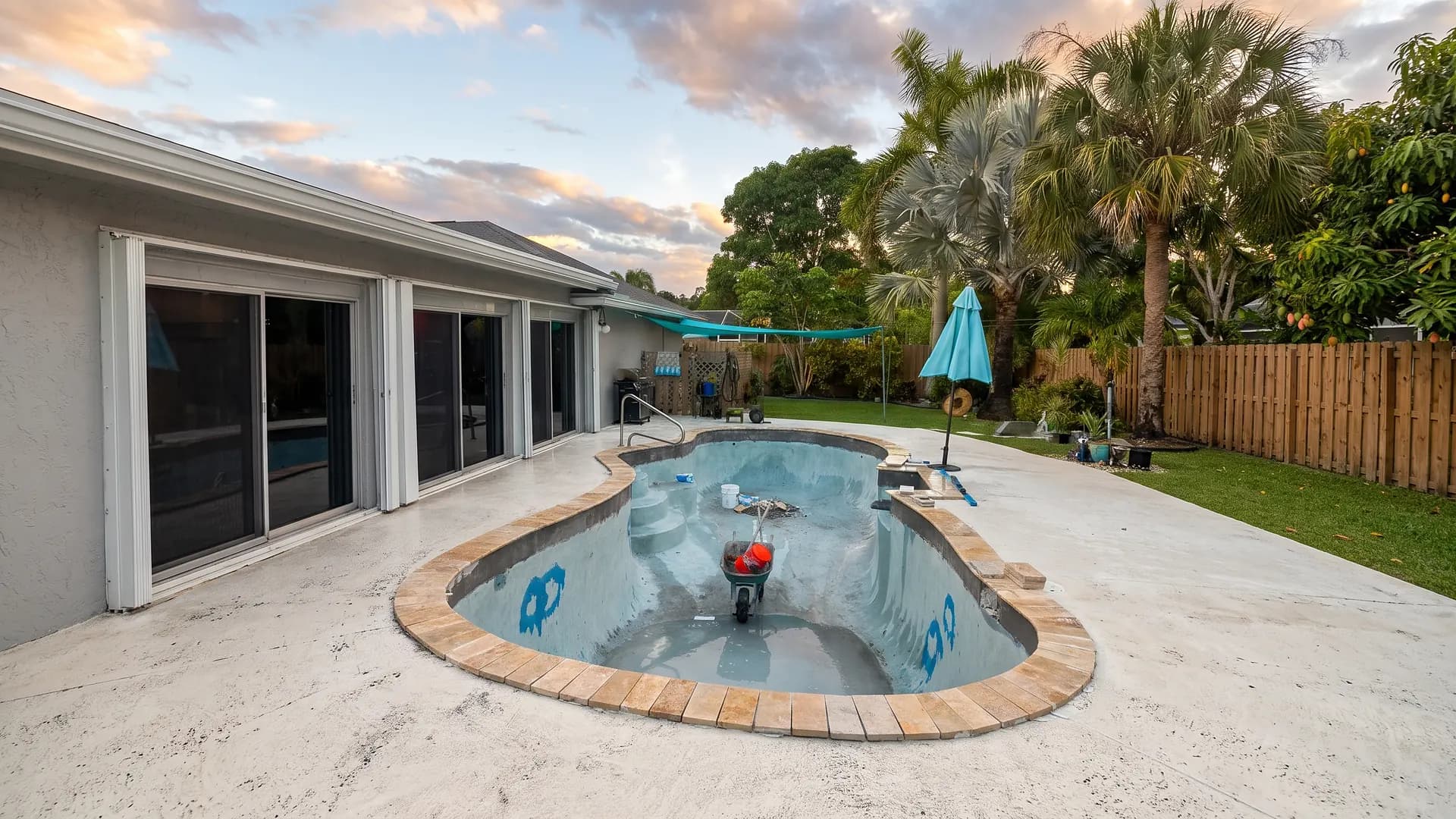 Travertine coping being set around a kidney shaped pool